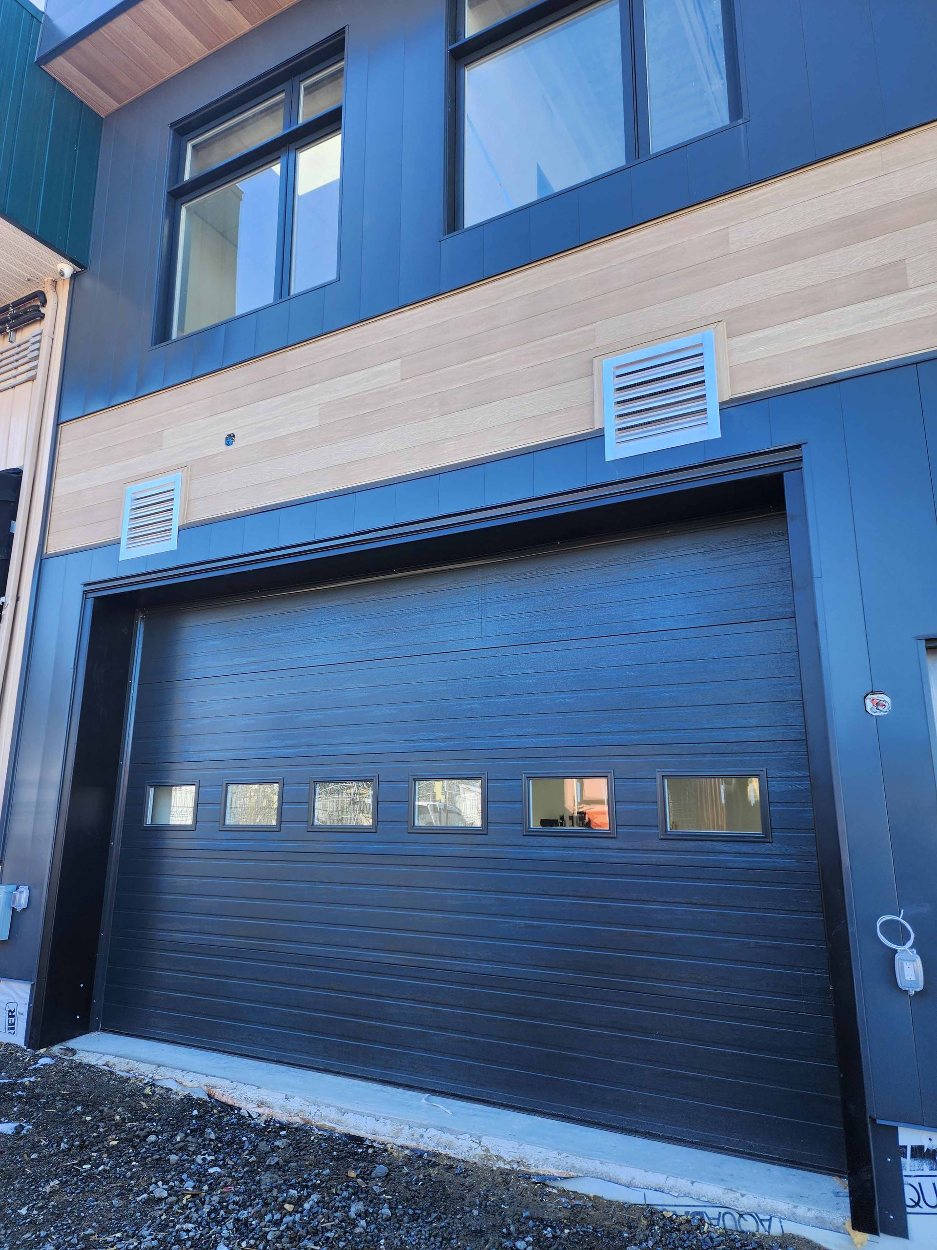 Une porte de garage noire se trouve sur le côté d'un bâtiment.