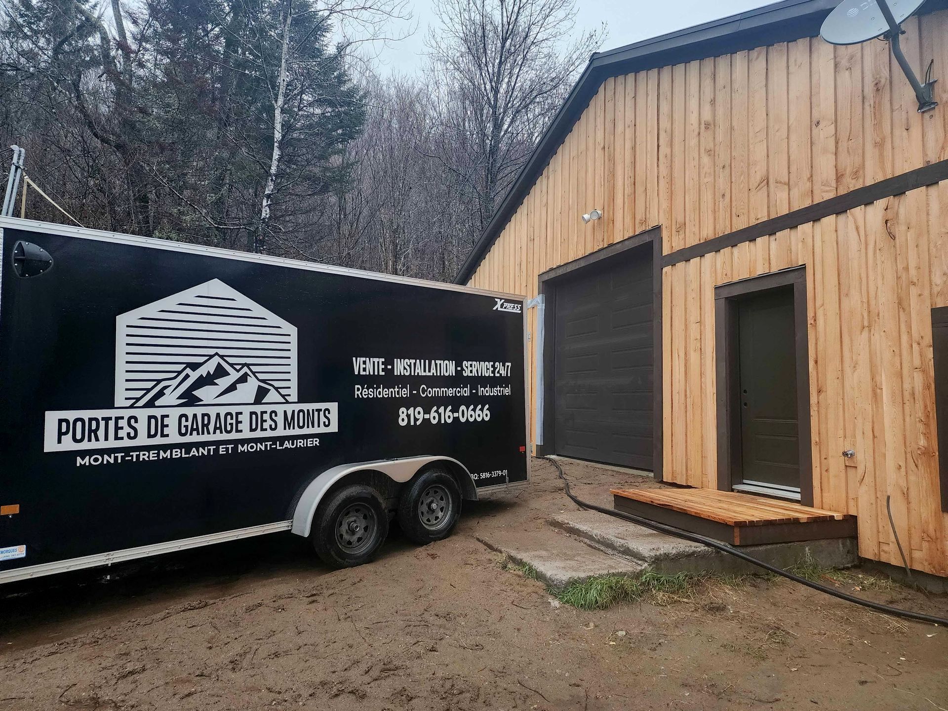 Porte de garage noire et blanche avec fenêtres, partiellement ouverte, à l'intérieur d'un garage en béton.