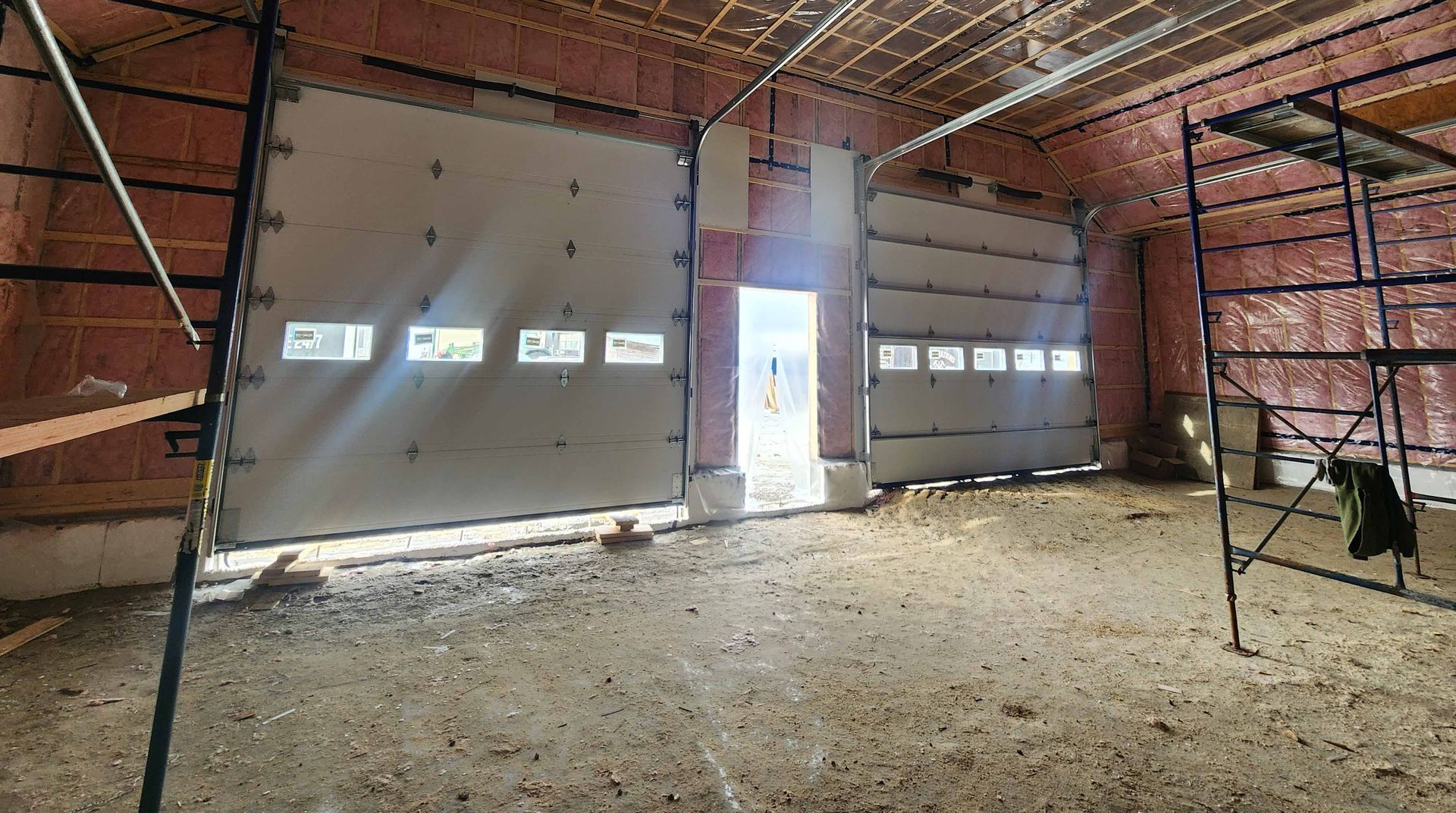 Intérieur d'un bâtiment en construction, montrant des portes de garage vitrées.