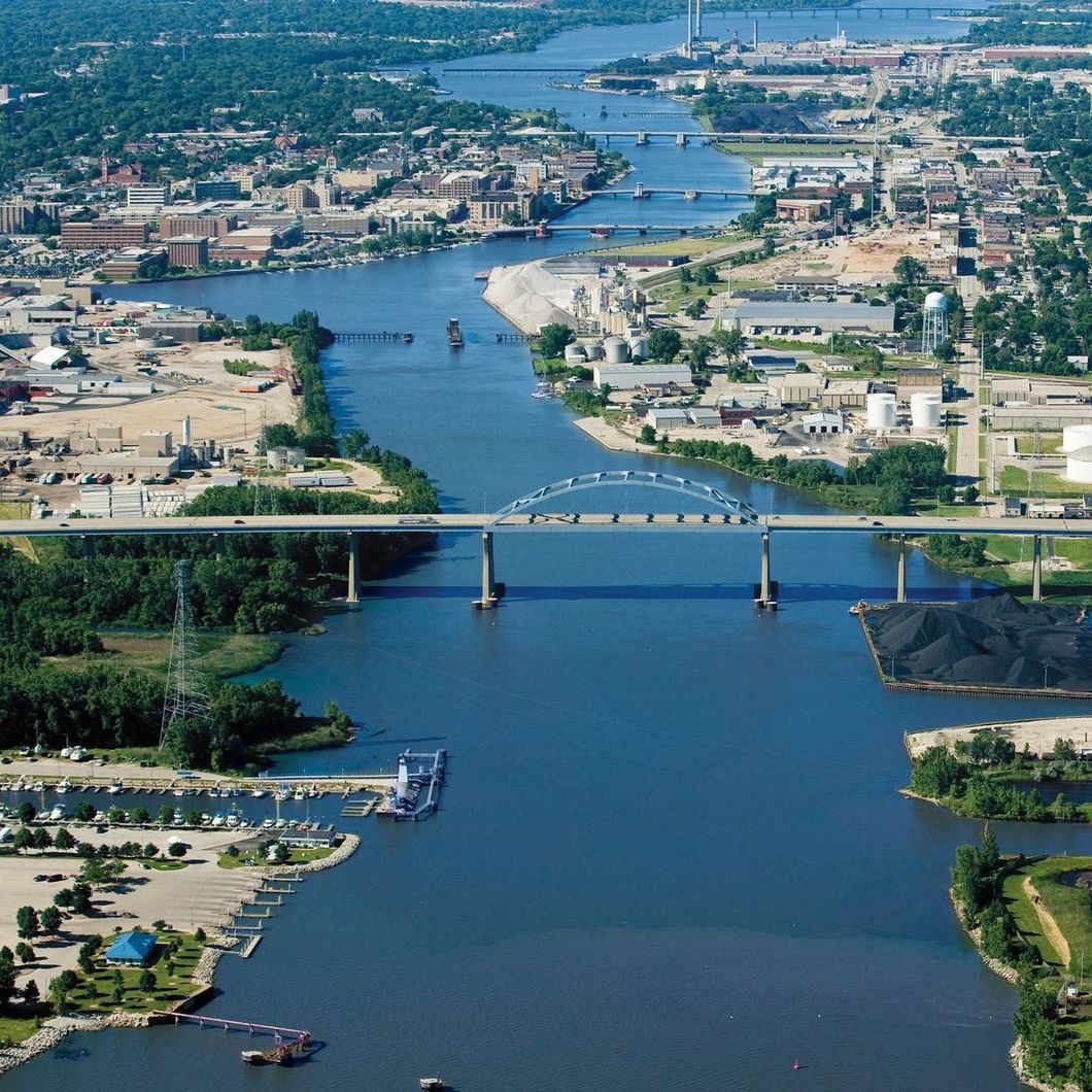 Aerial view of a blue river flowing through a city, crossed by bridges and lined with buildings and greenery