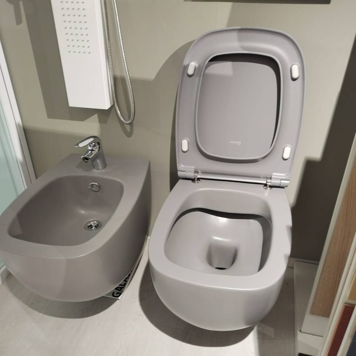 Bagno accessibile con lavabo grigio e sedile del water aperto.
