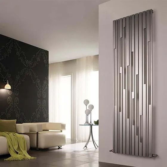 Soggiorno moderno con divano verde, tende trasparenti, termosifone a parete alto color argento e pannello decorativo.