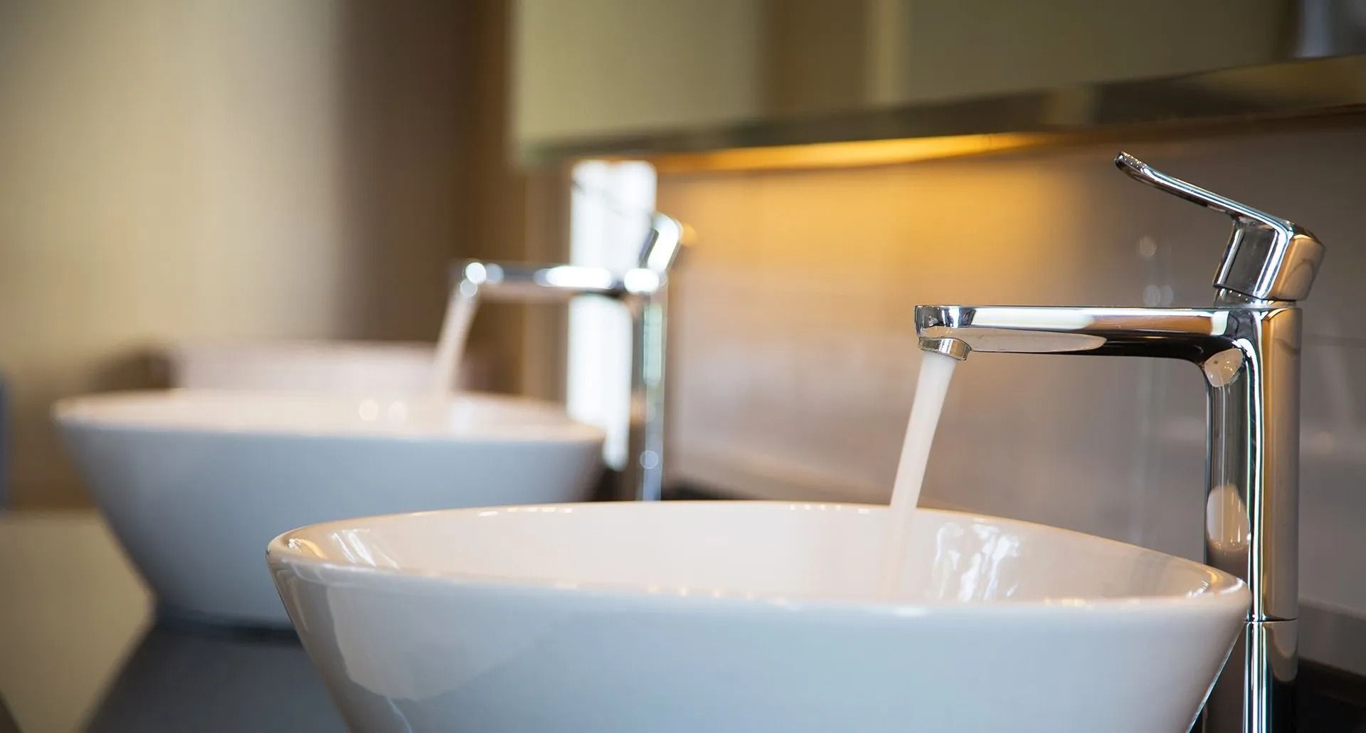 Due lavabi da bagno bianchi con rubinetti cromati su un piano di lavoro