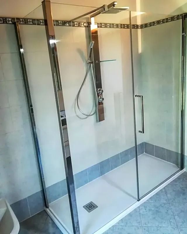 Cabina doccia moderna in vetro con finiture cromate e pavimento piastrellato, vista dal bagno.