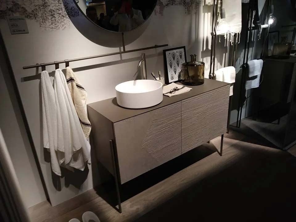 Mobile bagno moderno con lavabo rotondo, specchio, porta asciugamani e pavimento scuro.