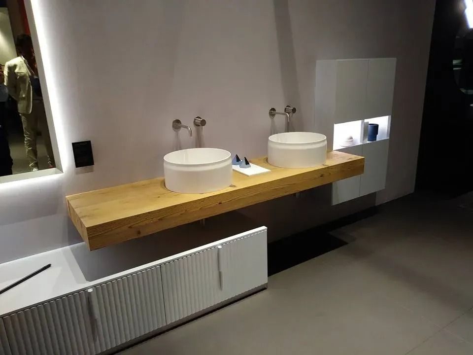 Mobile bagno moderno con due lavabi rotondi su un piano in legno e un radiatore sottostante.