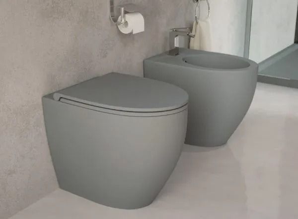 Bagno moderno con due WC grigi dal design scultoreo, affiancati vicino alla doccia.