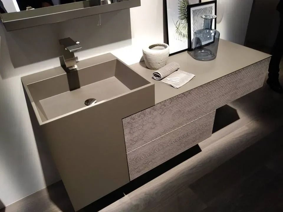 Mobile bagno moderno con lavabo beige, accessori da appoggio e specchio a parete sopra un mobiletto in legno scuro.