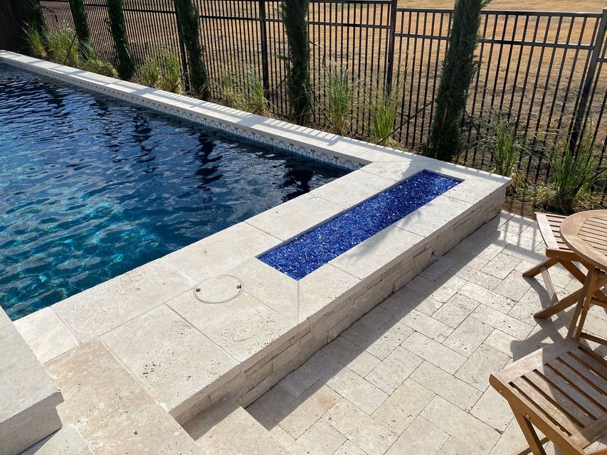 A swimming pool with a table and chairs next to it.