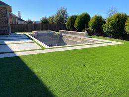 A backyard with a swimming pool and a lush green lawn.