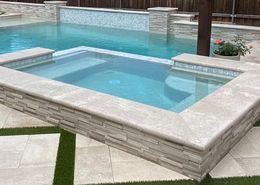 A large swimming pool with a hot tub in the middle of it.