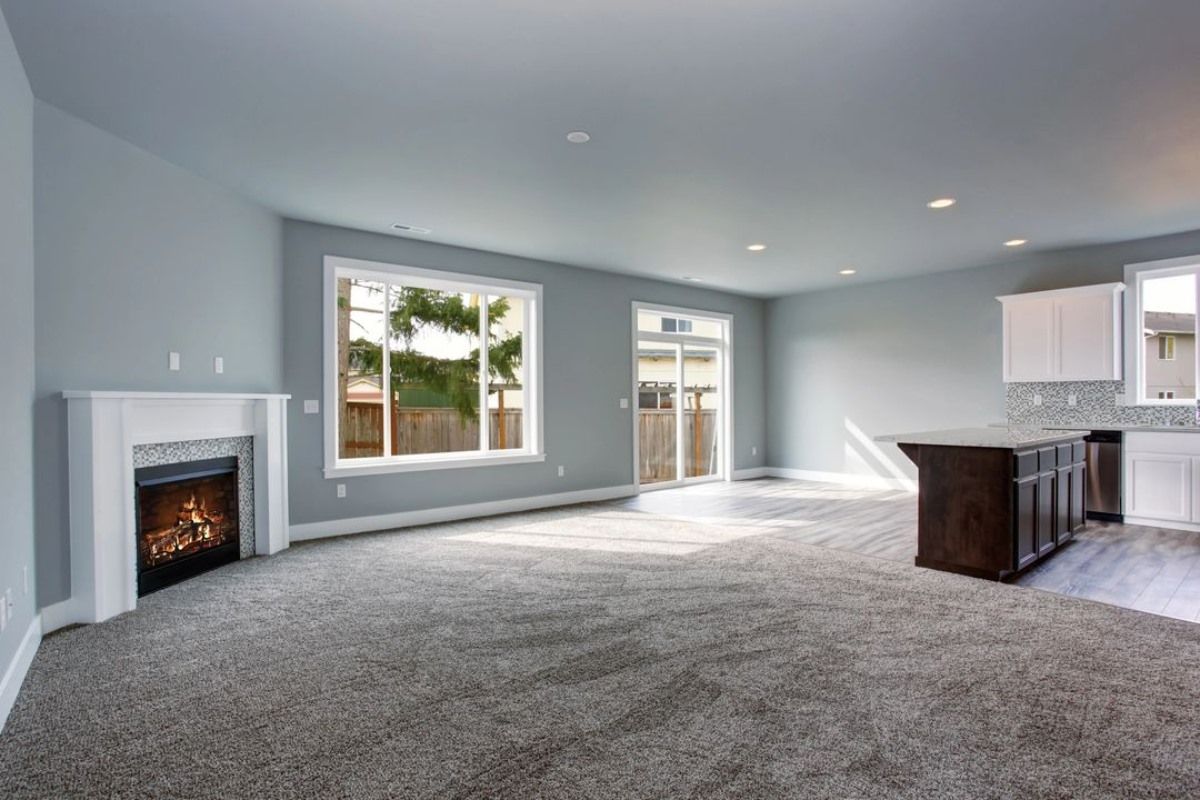 an empty living room with a fireplace and a large window .