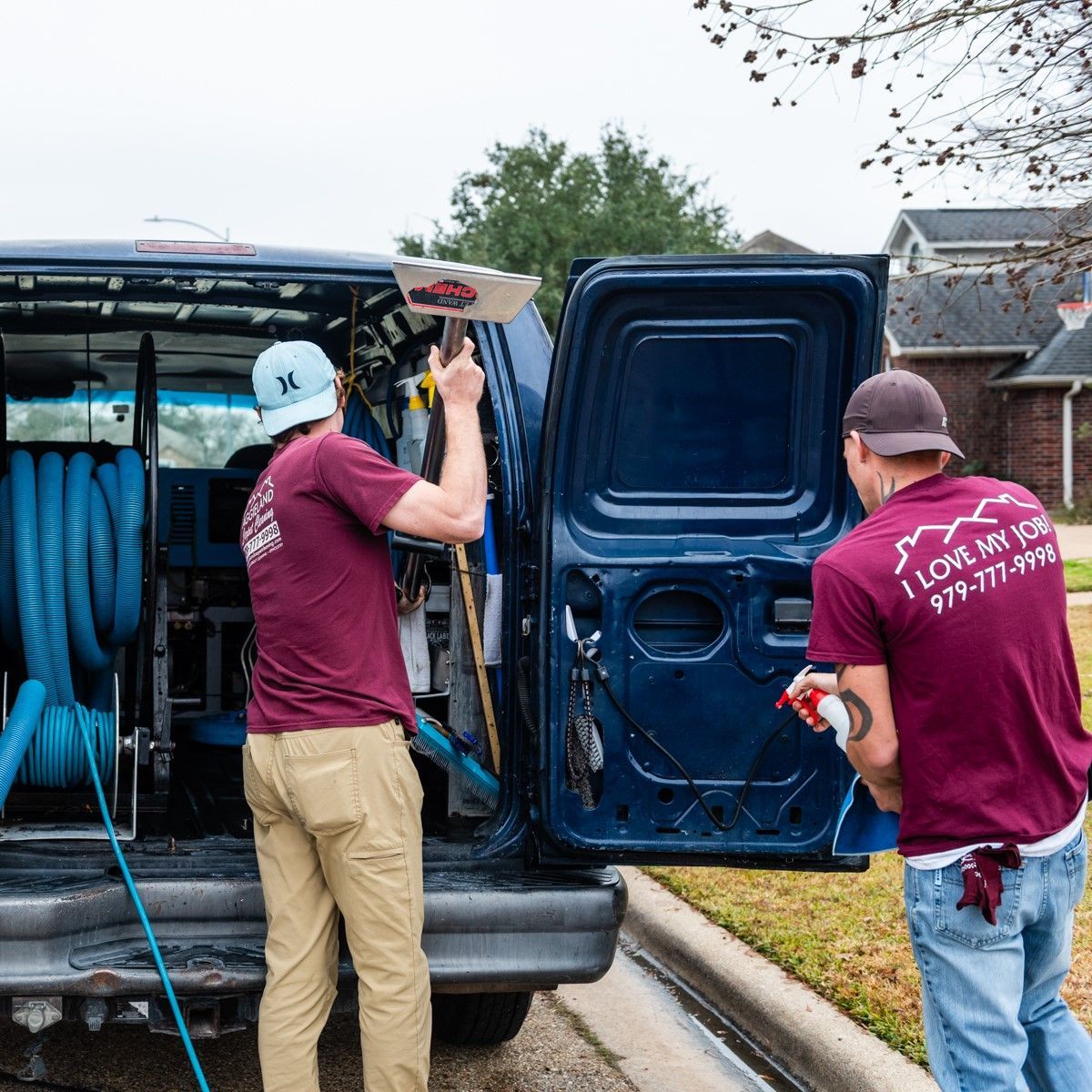two men are standing in front of a blue van with the door open