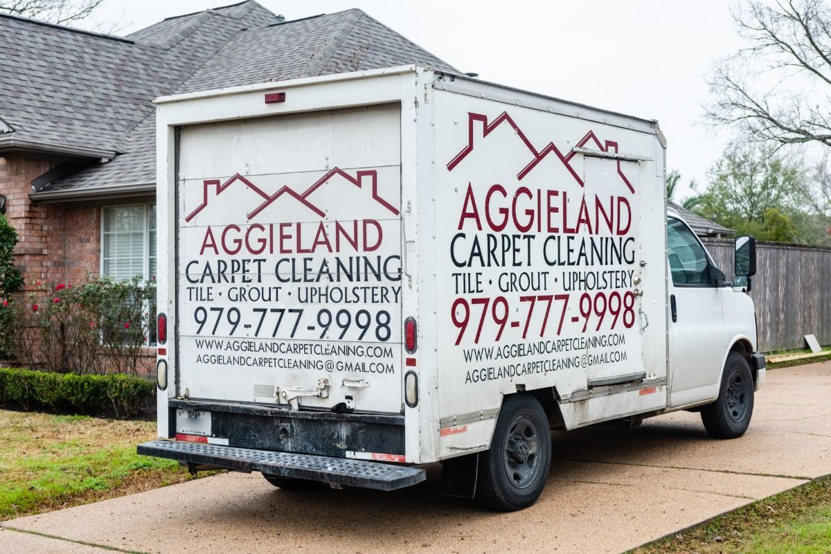 a white carpet cleaning truck is parked in front of a house .