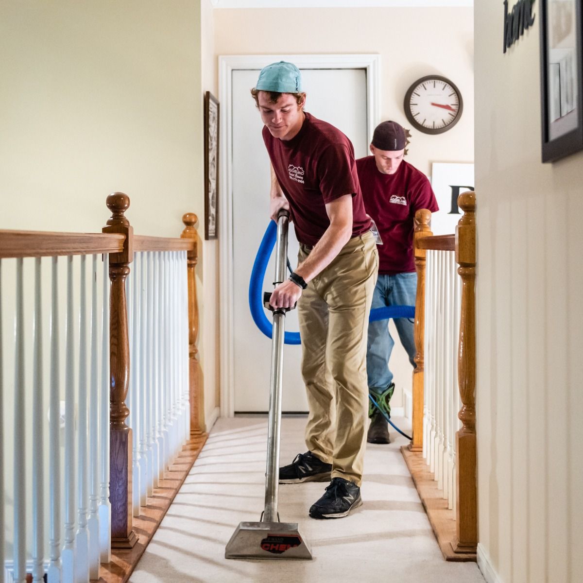 Residential carpet cleaning technician using steam cleaner on hallway carpet