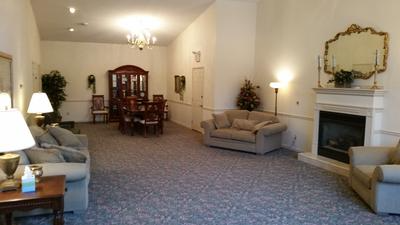 Spacious living room with sofas, fireplace, dining table, and carpeted floor in warm lighting