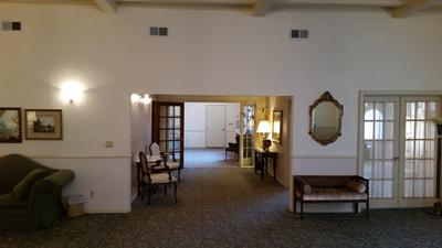 Spacious living room with sofas, wall sconces, framed art, and open doorways to adjacent rooms