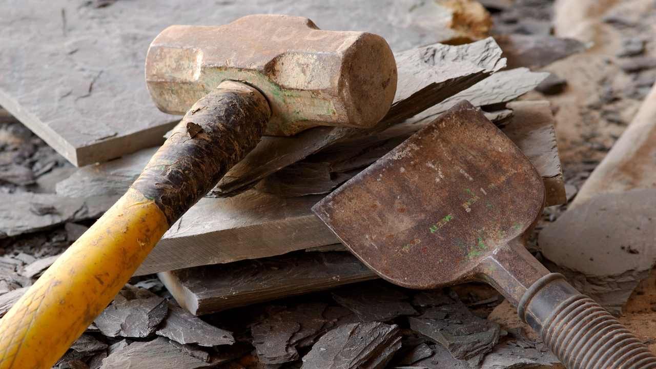 Masonry trowel and hammer resting on a job site surface for block and retaining wall construction