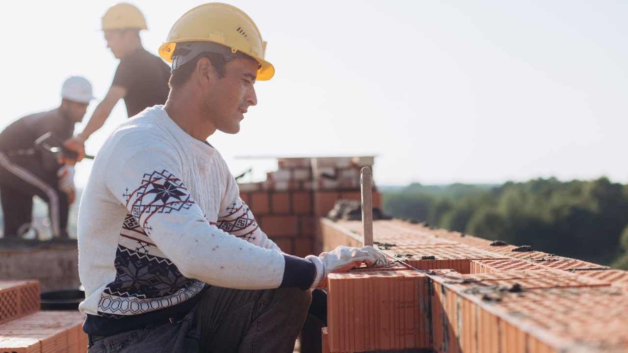 “Worker setting masonry blocks in place with a trowel during a block and retaining wall installation”