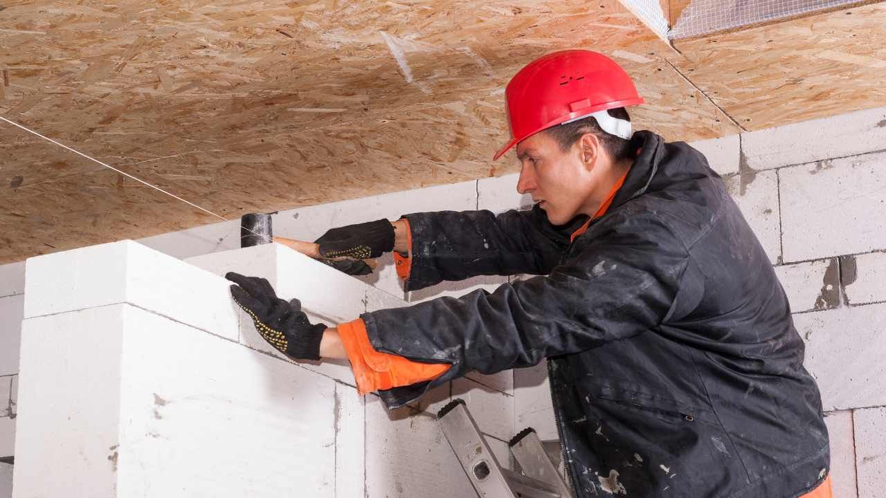 Worker building a block wall under a covered structure during a block and retaining wall project