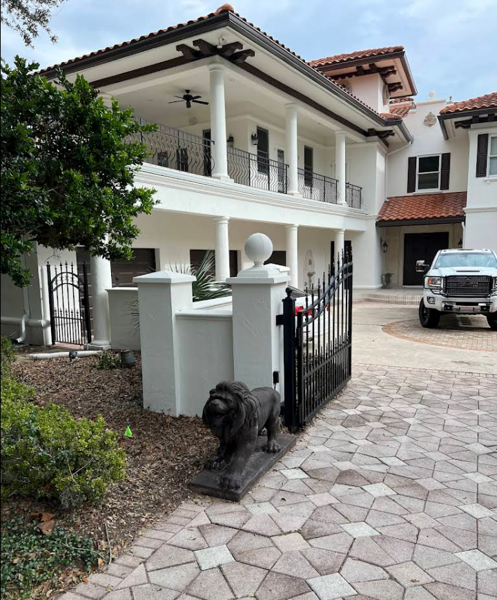 Driveway and front entrance of a white house with columns, a black dog, and a parked SUV.