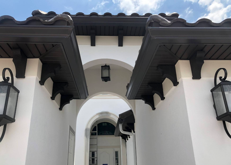White stucco archway with dark wooden eaves and lanterns leading to a courtyard entrance