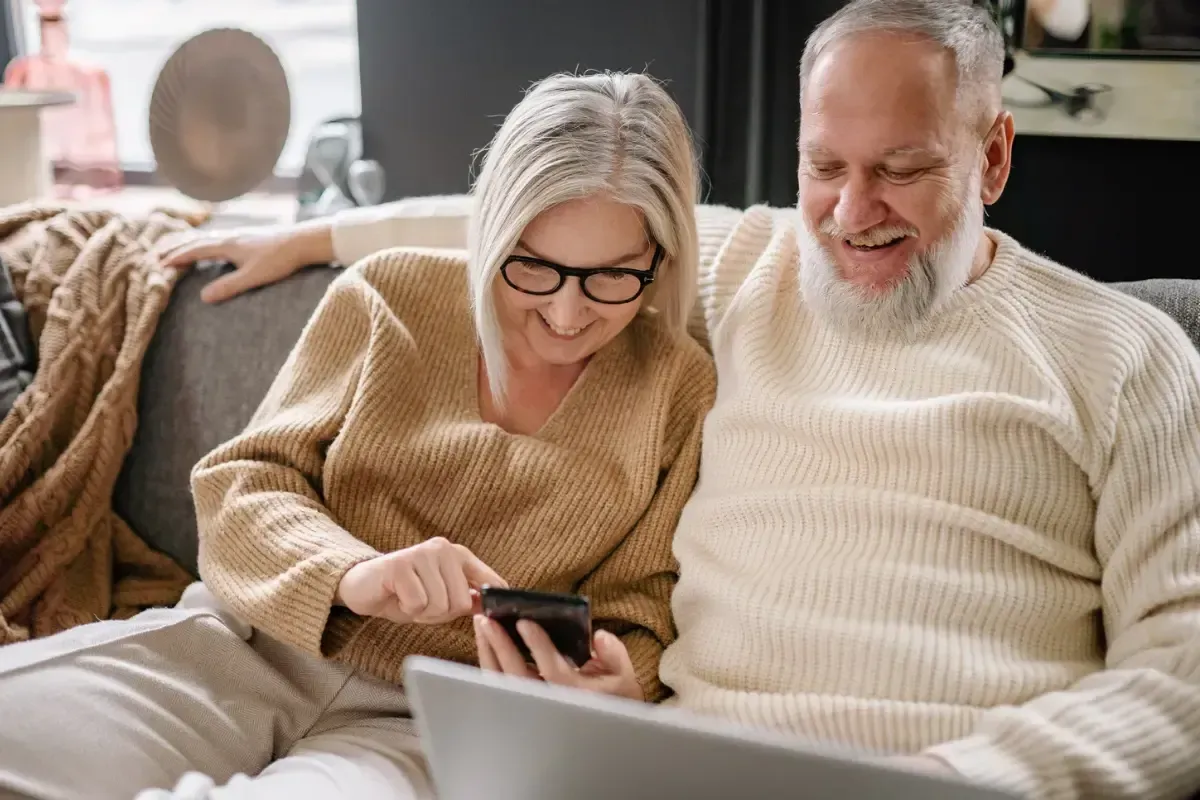 Happy couple looking at a laptop and phone.