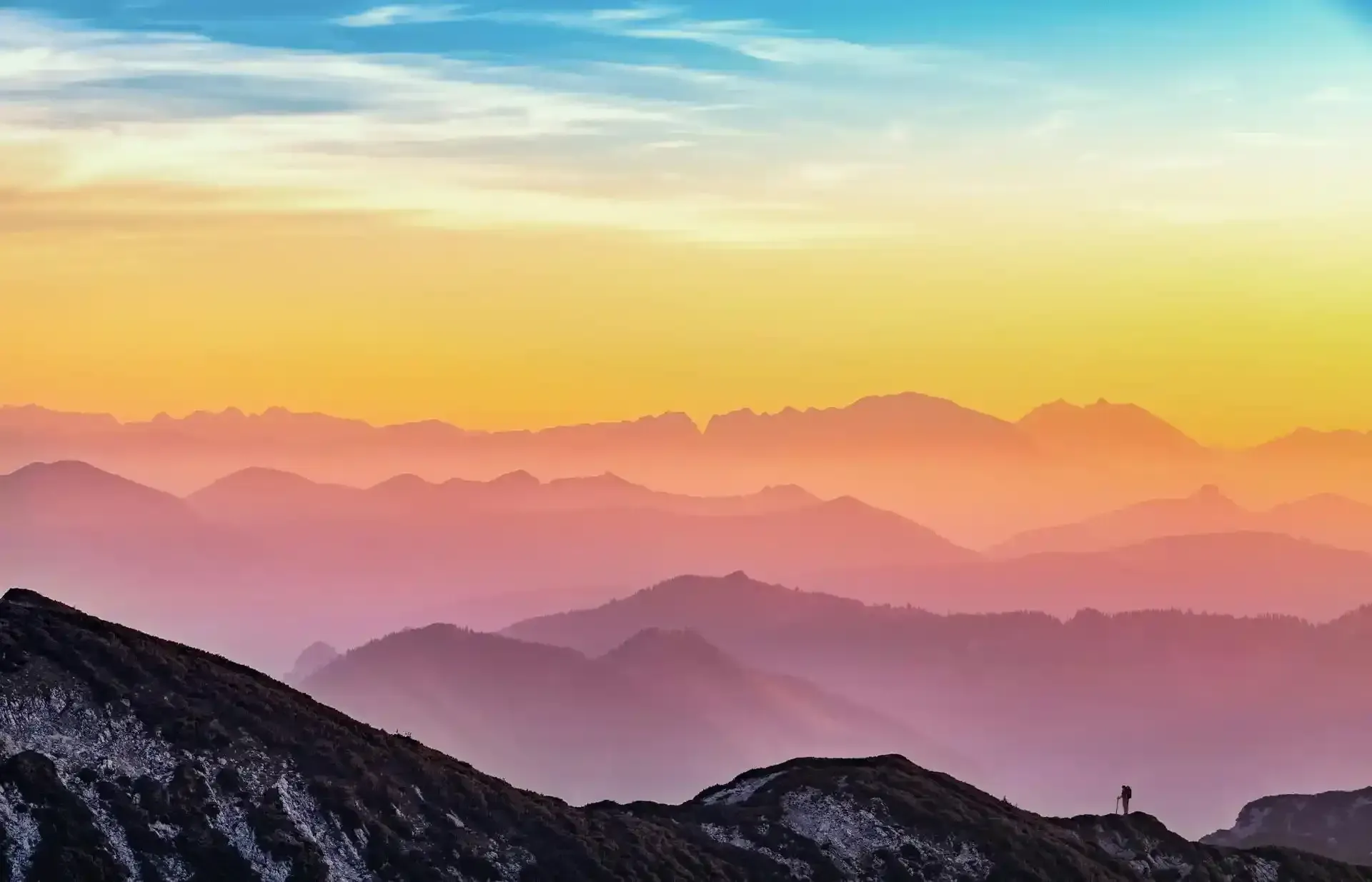 A man staring out at a mountain landscape while standing on one.