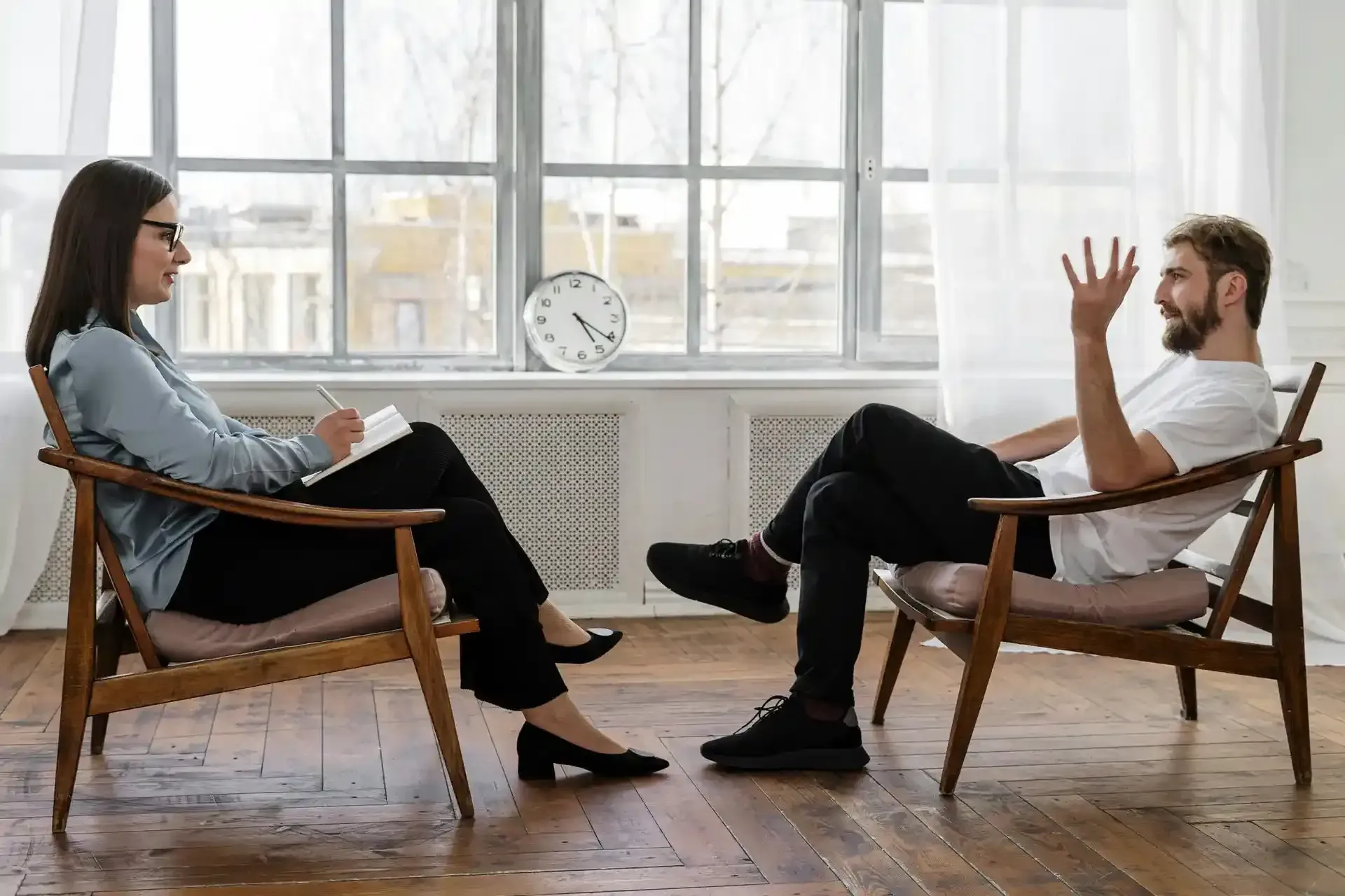 a woman therapist sitting across from a male client in an office