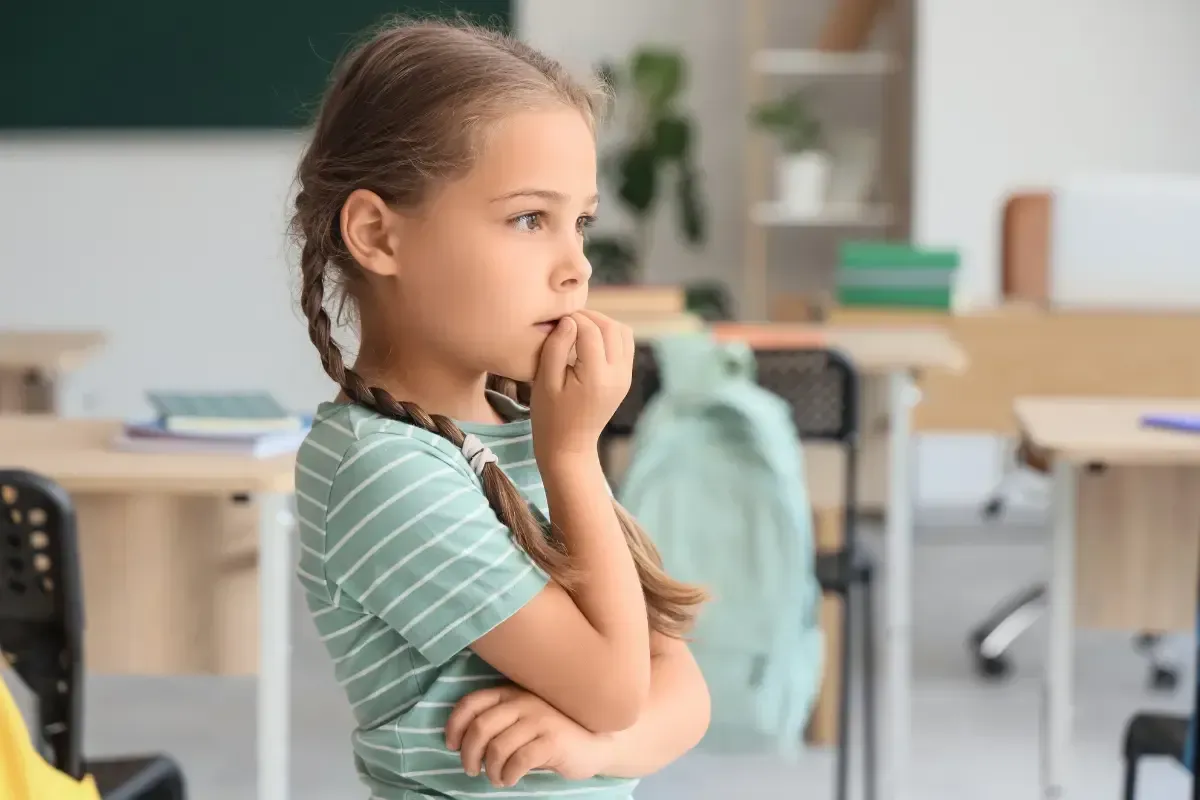 Girl biting her nails in a classroom.