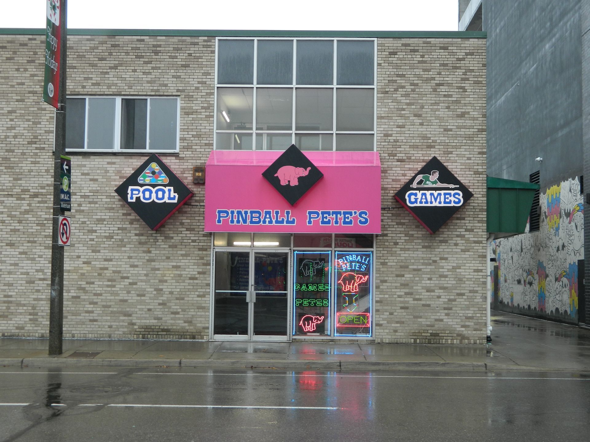 Pinball Pete's arcade with pink awning and neon signs; brick building exterior.