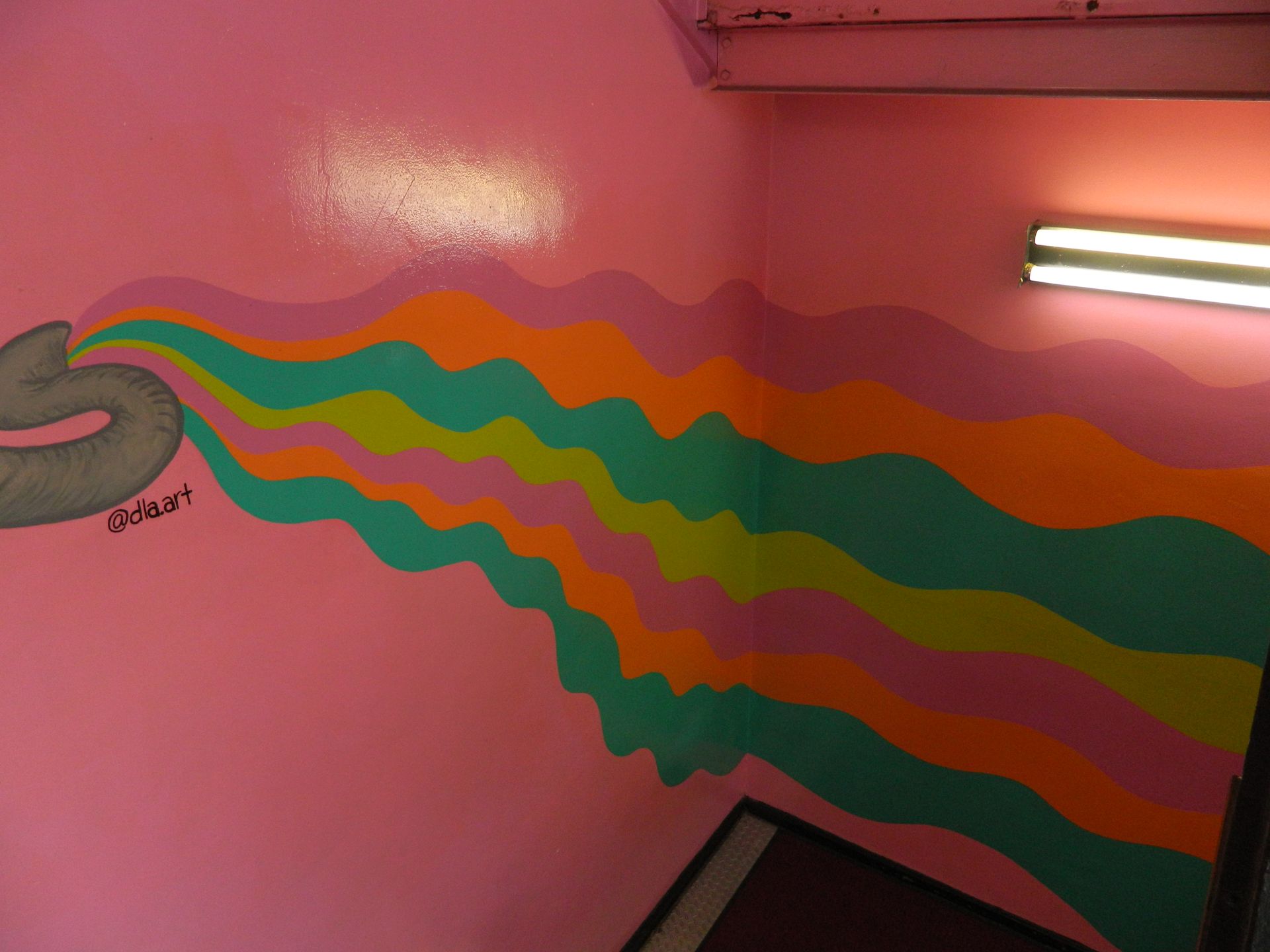 Pink wall with a painted, colorful wavy design flowing from a grey shape.