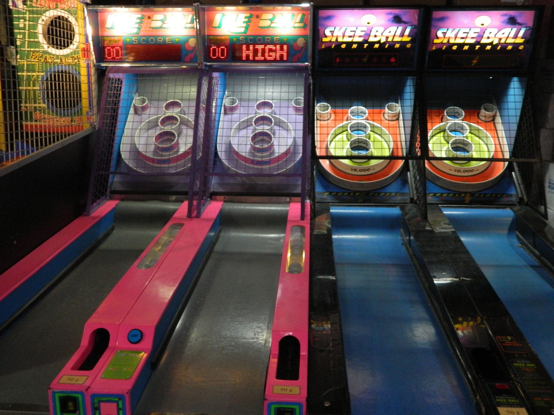 Skee-Ball arcade game machines with pink and blue lanes. Each has numbered scoring holes and a digital display.