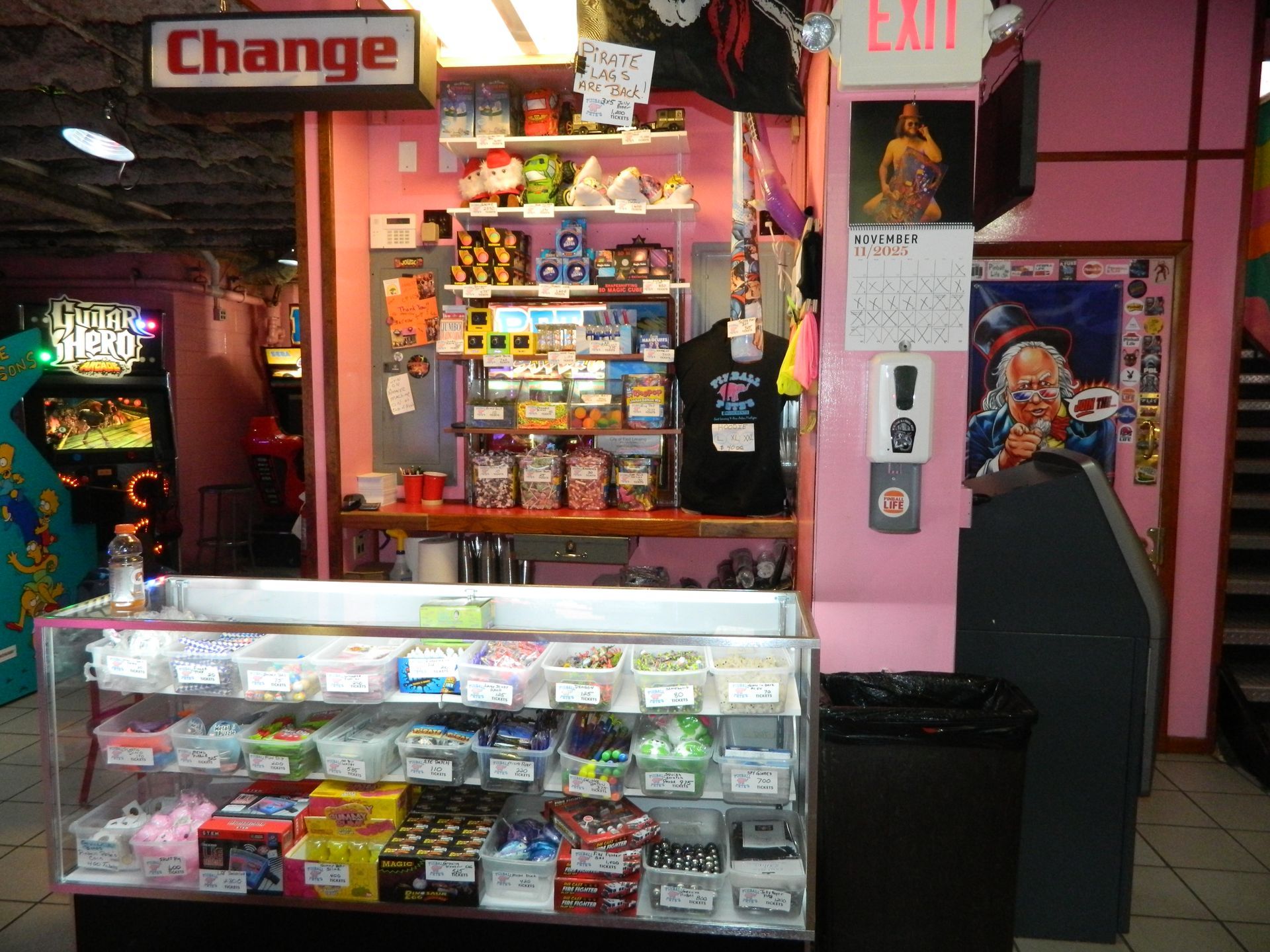 Pink arcade game prize counter with candy, toys, and t-shirts. 