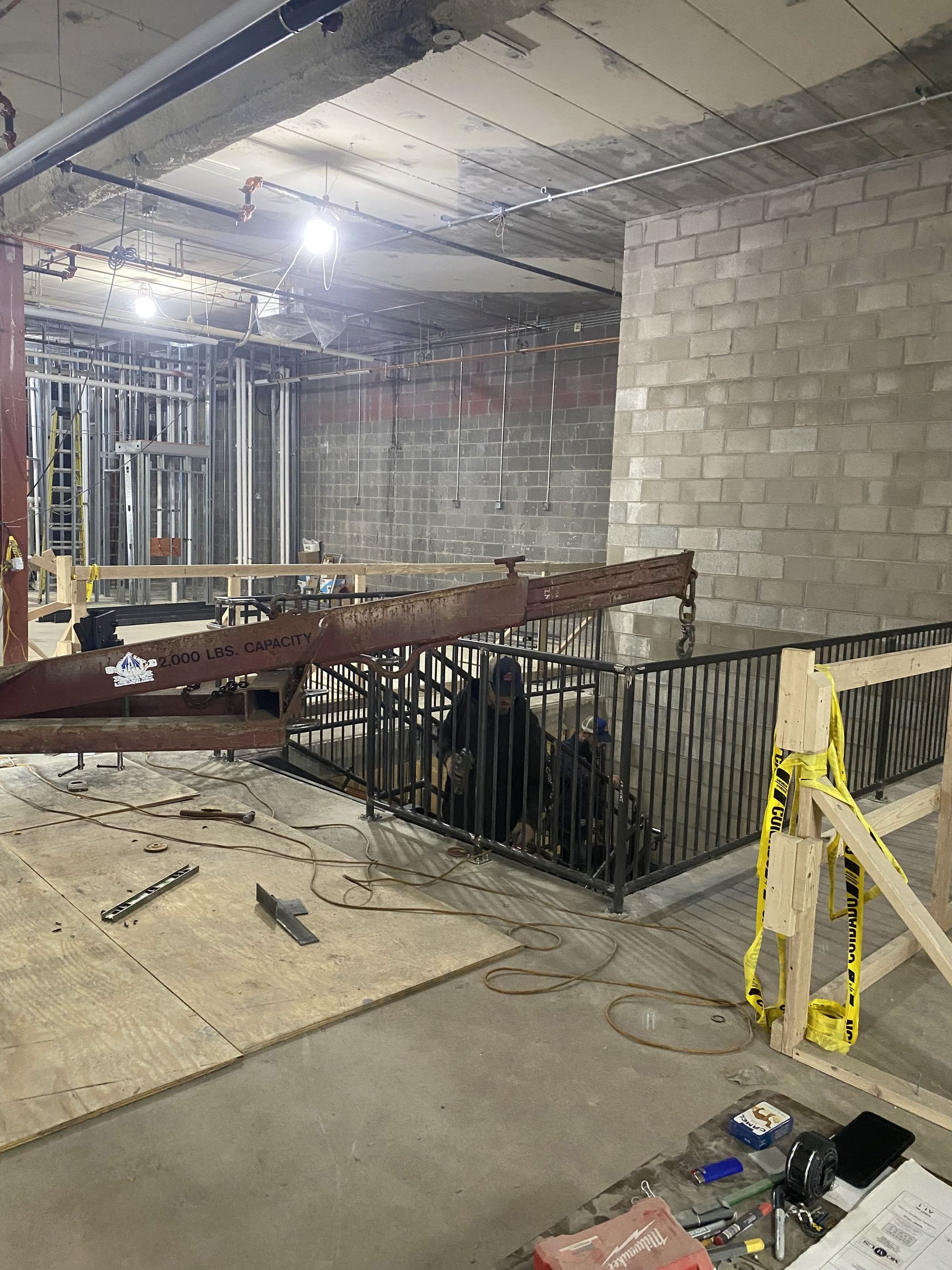Construction site with unfinished walls and metal staircase; tools and materials scattered on the floor.
