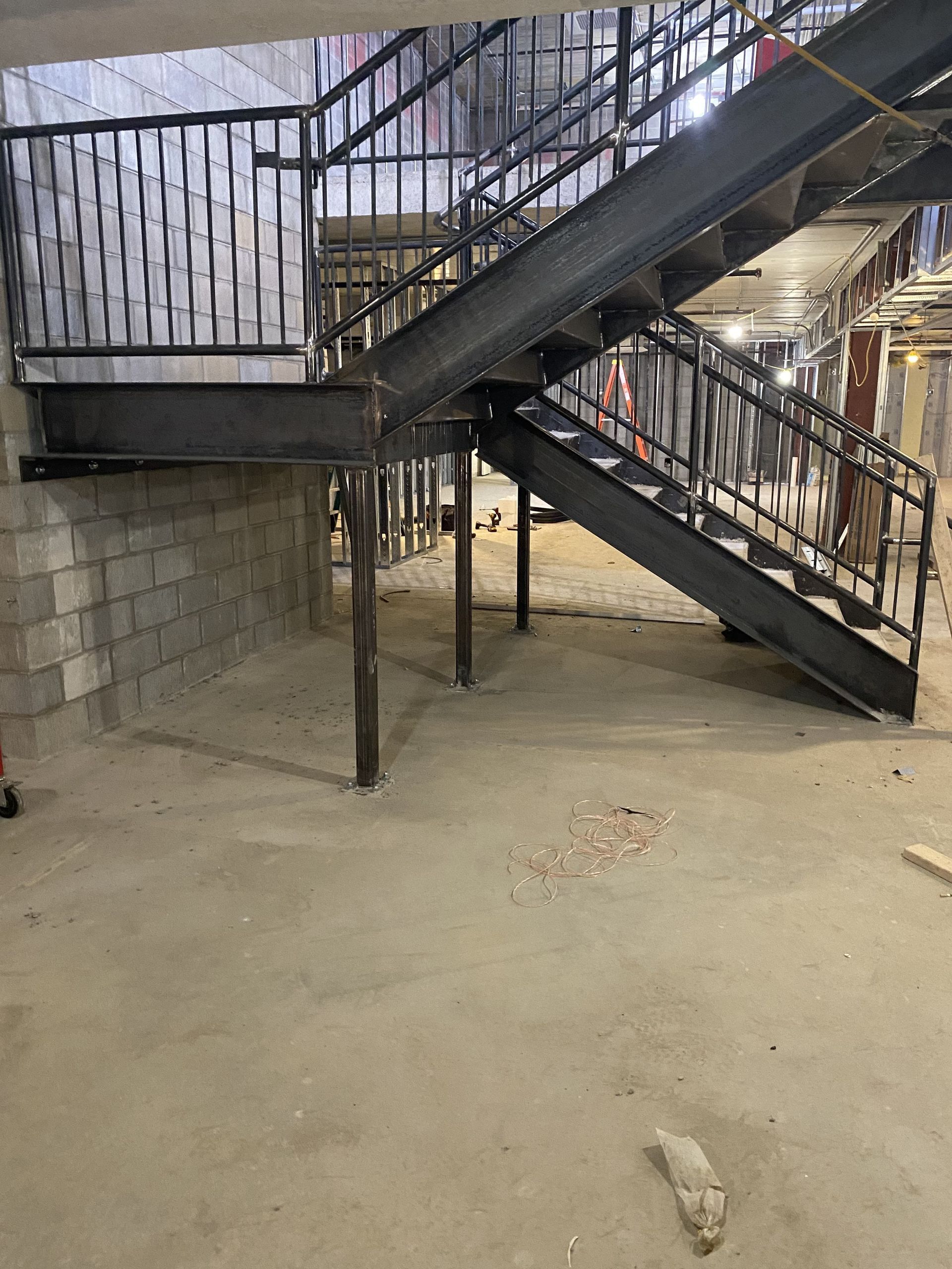 Steel staircase under construction in a concrete building. Supports visible.