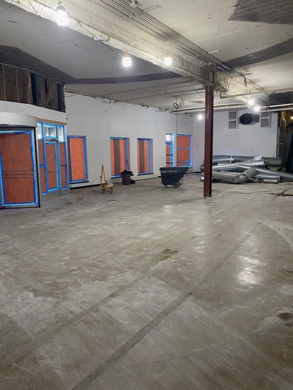 An empty room undergoing construction with unfinished walls, a concrete floor, and exposed ceiling beams.