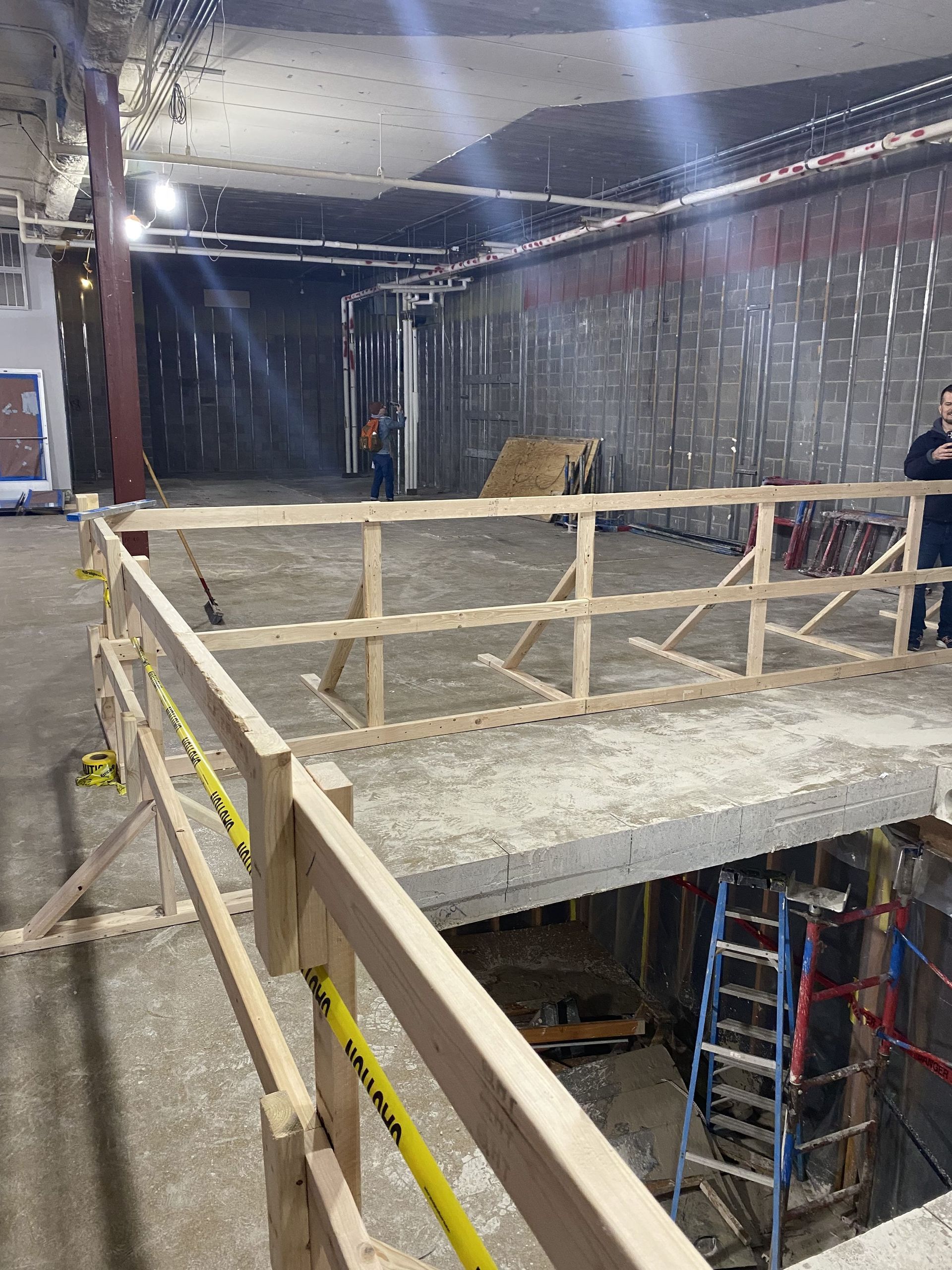 Construction site with a temporary wooden platform, railing, and ladder.