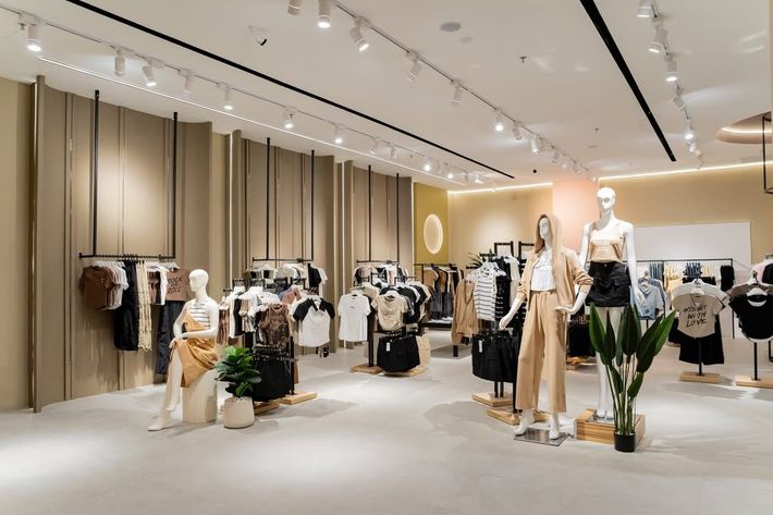 Modern clothing boutique with neutral-toned apparel displays and mannequins in a bright, minimalist showroom