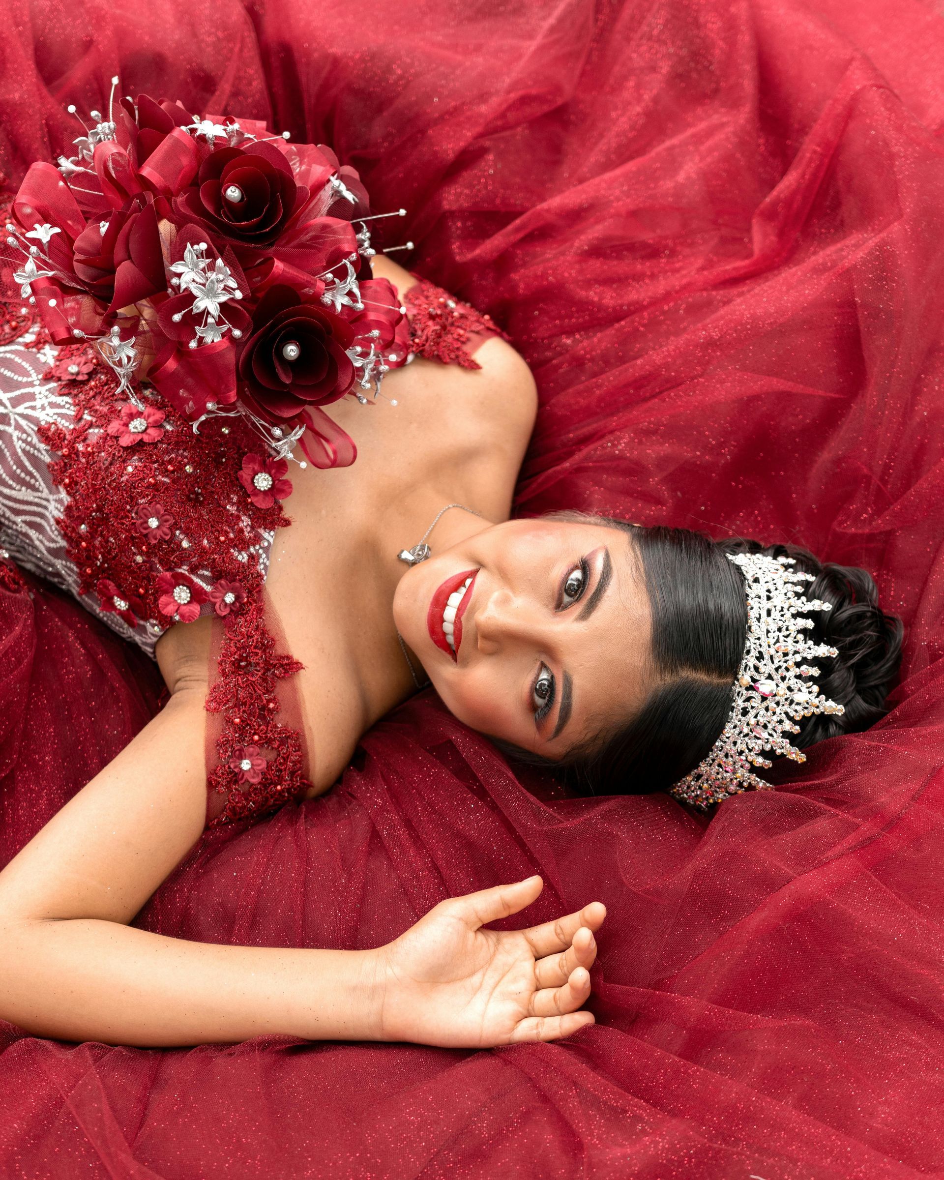 A woman in a red dress and tiara is laying down