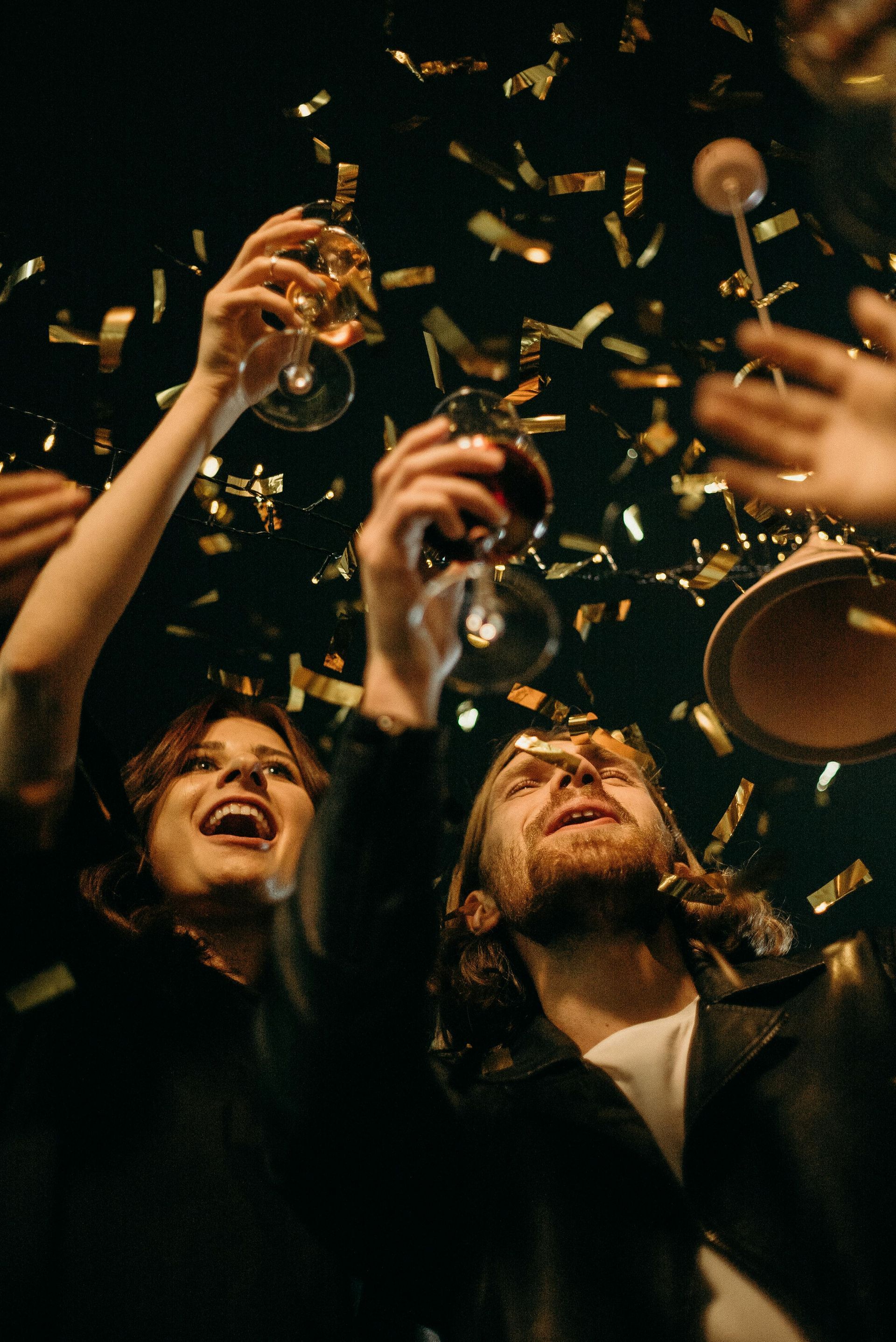 A group of people are toasting with wine glasses and confetti.
