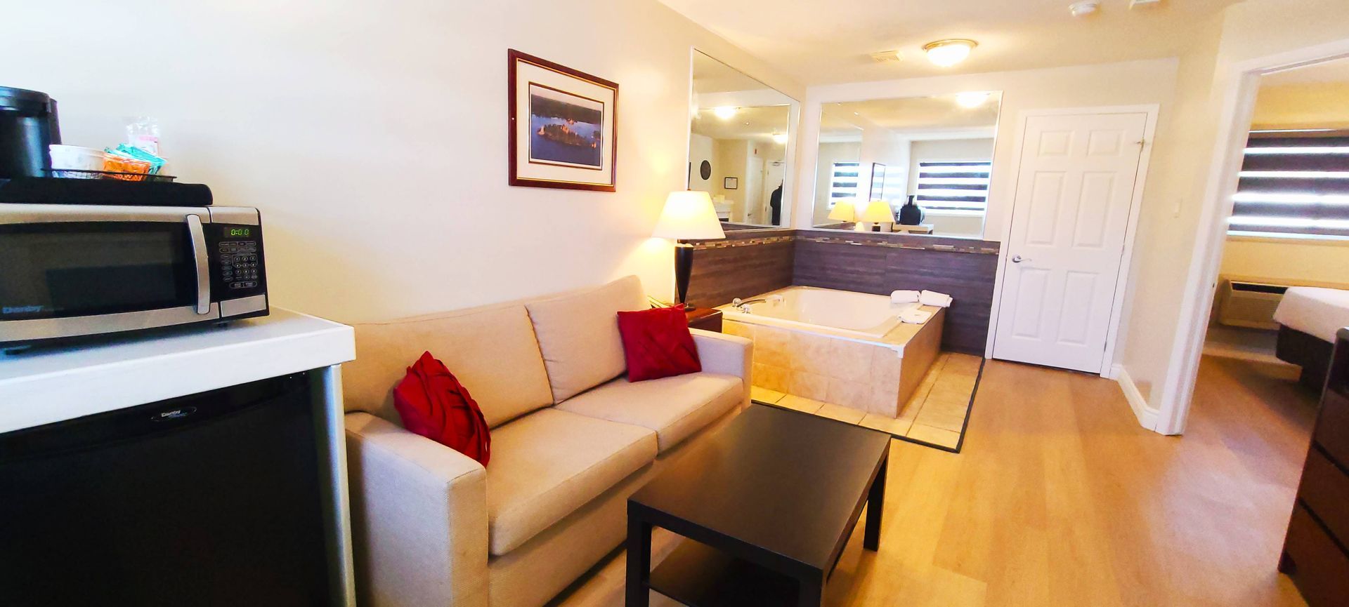 a living room with a couch , coffee table , microwave and jacuzzi tub .