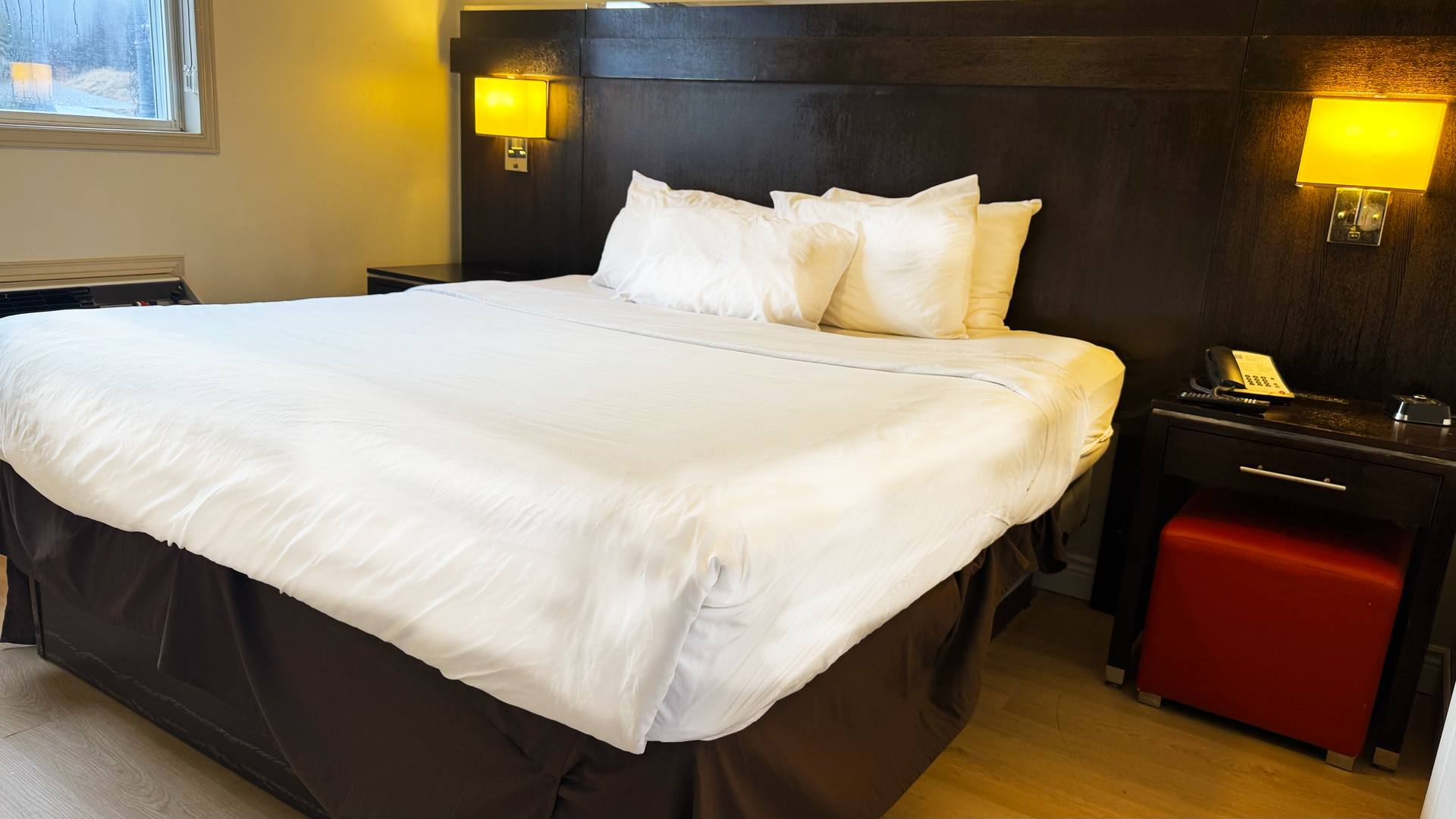 Hotel bedroom with a made bed, nightstands, and wall sconces.