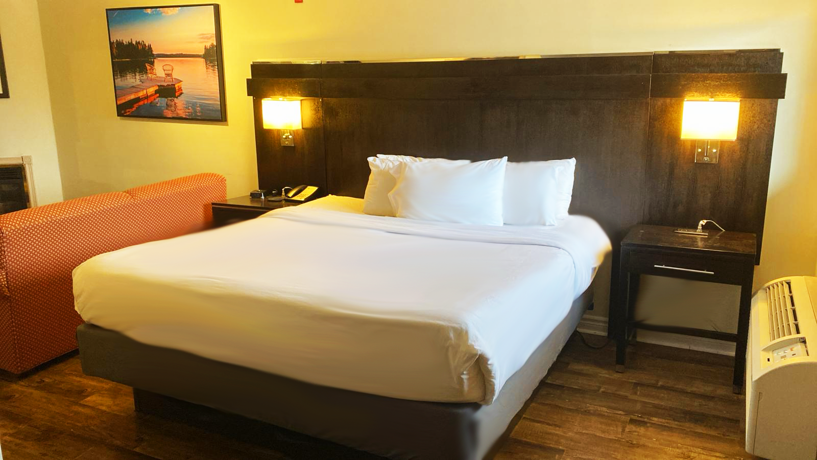 Hotel room with a bed, nightstands, a sofa, and wall art.