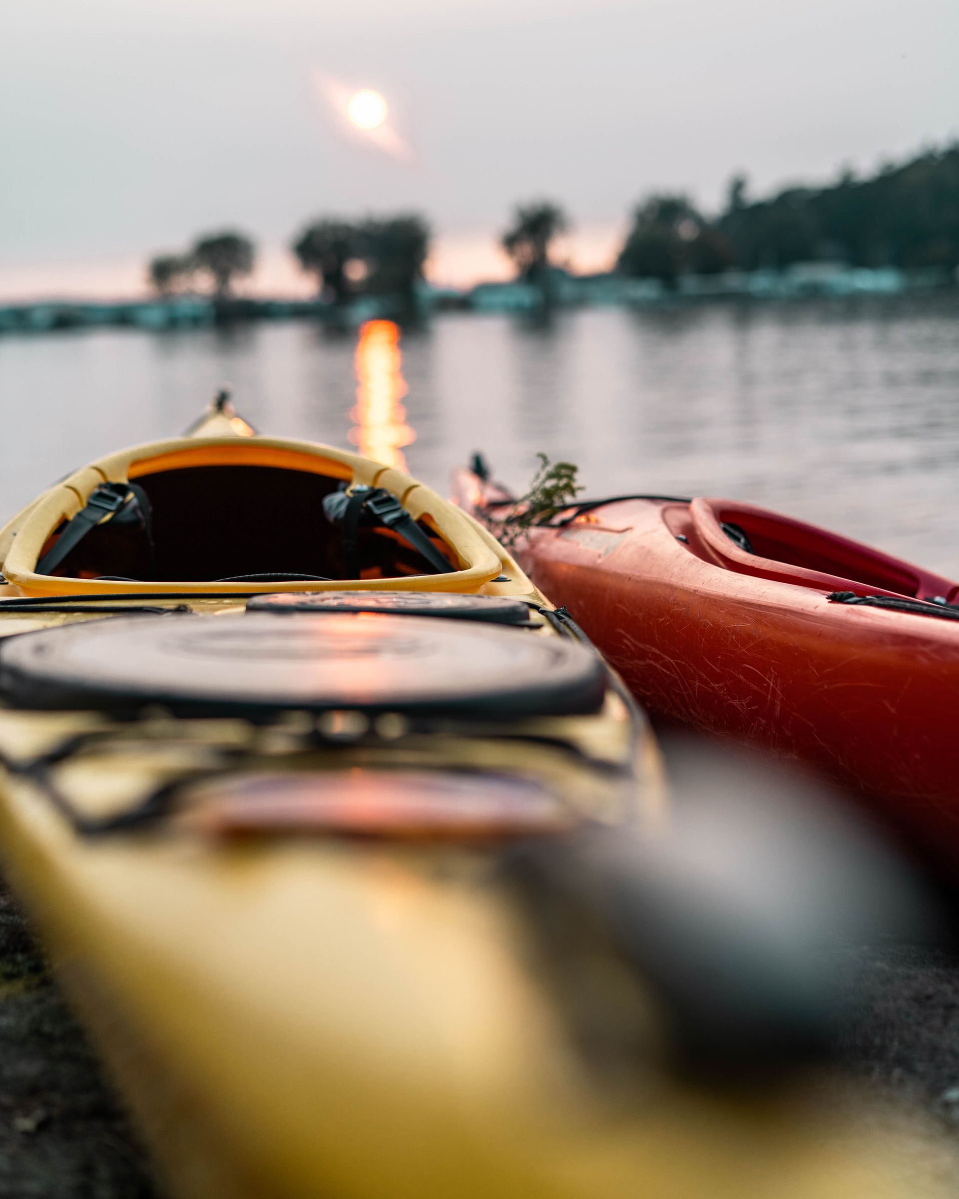 two kayaks are sitting on the shore of a lake .