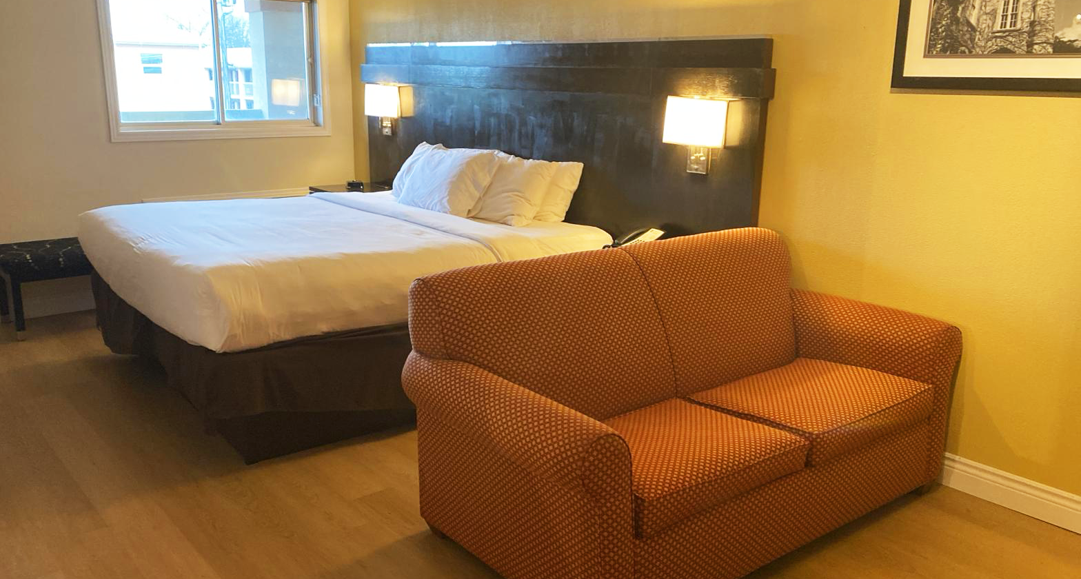Hotel room with bed, sofa, and a window.