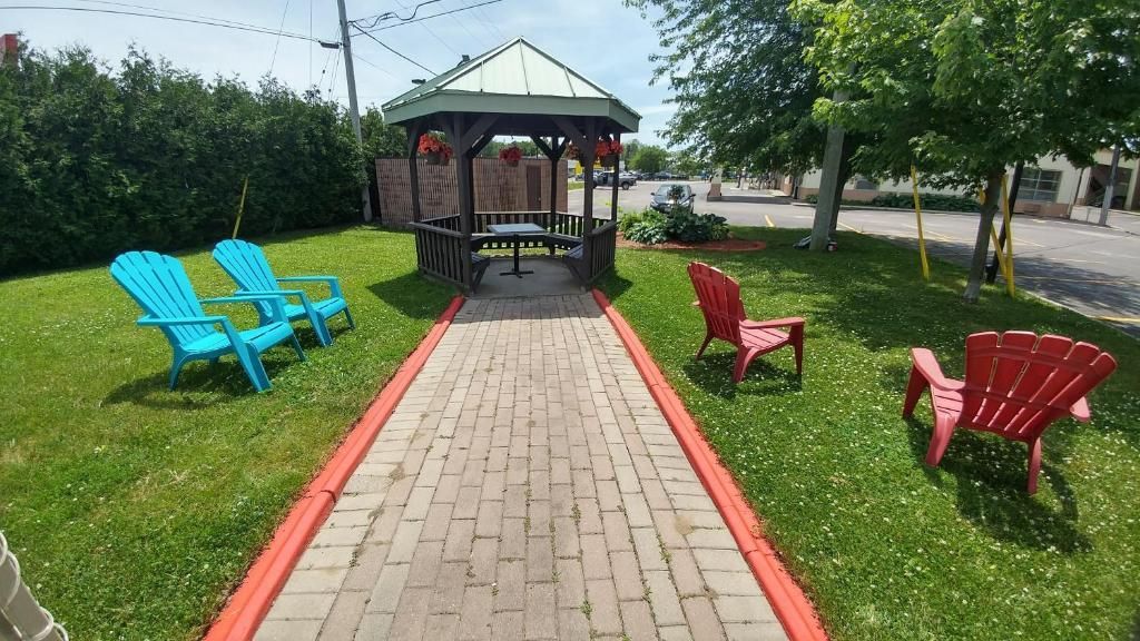 a brick walkway leading to a gazebo with blue chairs and red chairs