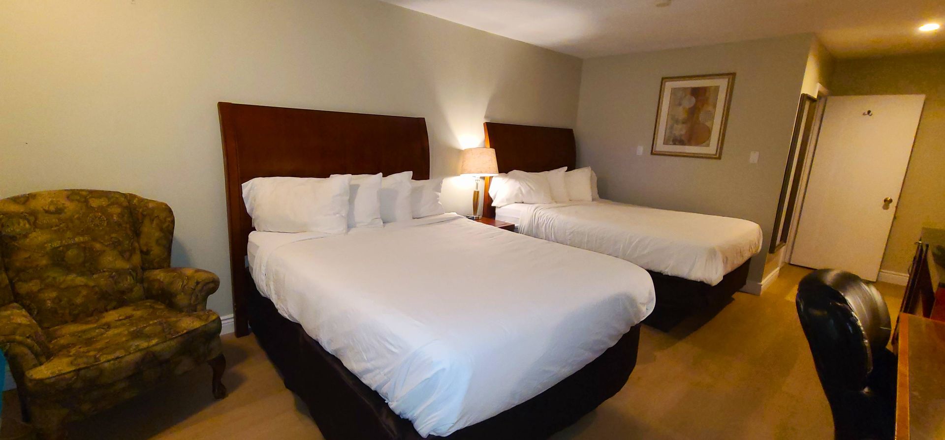 a hotel room with two beds , a chair and a fan .