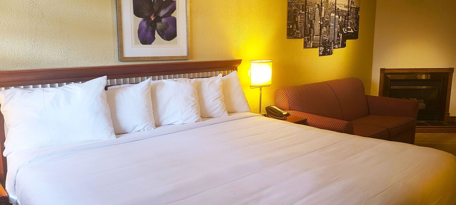 a hotel room with a king size bed , chair and fireplace .