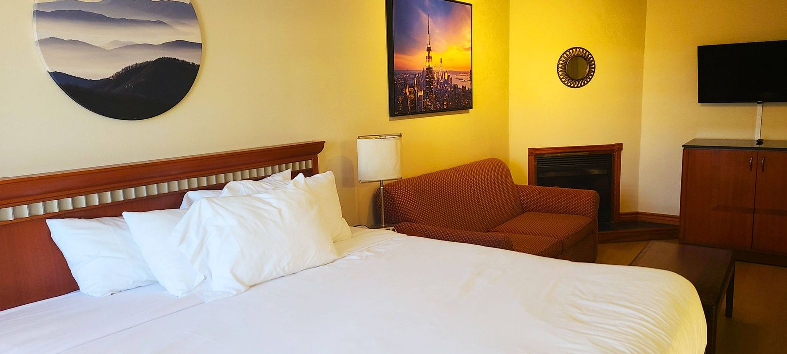 a hotel room with a king size bed , couch and television .